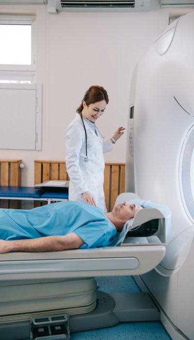 attractive-smiling-doctor-preparing-man-for-scanning-in-mri-machine