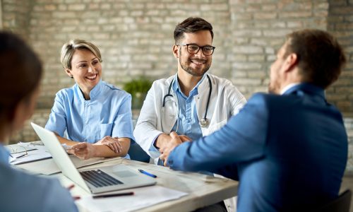 Group of healthcare workers greeting a financial advisor during the meeting in the office. Focus is on young doctor.